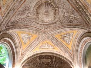 Soffitto a volta affrescato in stile rinascimentale, con decorazioni a rilievo, motivi floreali e scene figurative nei pennacchi giallo-ocra; al centro un rosone circolare e, in basso, un cartiglio con la scritta latina ‘ET LVCI ET AMICIS